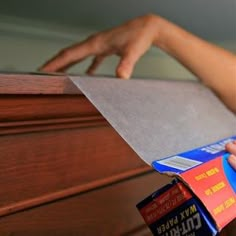 someone is opening up a piece of paper on top of a dresser