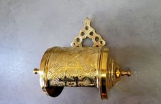 a golden toilet paper dispenser mounted on a wall with an ornate design