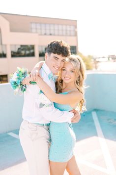 a young man and woman hugging each other in front of a building with a pool