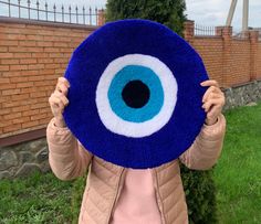 a woman holding up a blue and white eyeball pillow