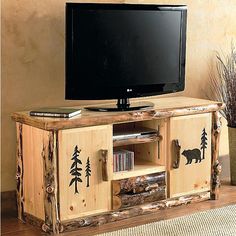 an entertainment center with a television on top of it and trees painted on the side