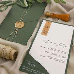 an envelope with a wax stamp and some twine on it next to a bottle of wine