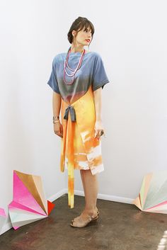 a woman standing in front of an assortment of umbrellas on the floor with her hands behind her back