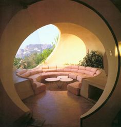 a living room filled with lots of furniture under a large round window on the side of a building