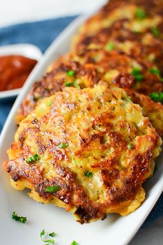 two fritters on a plate with sauce and parsley