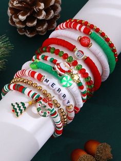 a stack of christmas bracelets sitting on top of a white tube next to pine cones