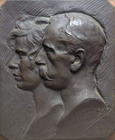 a close up of a metal plaque with three men's heads in profile on it