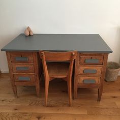 a wooden desk with two chairs and a vase on the top shelf next to it