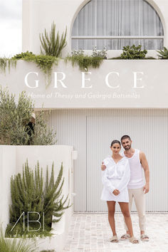 a man and woman standing in front of a building with greenery on the side