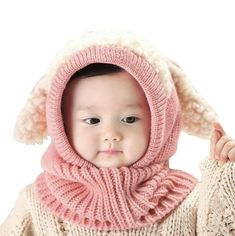 a baby wearing a pink knitted hat and scarf