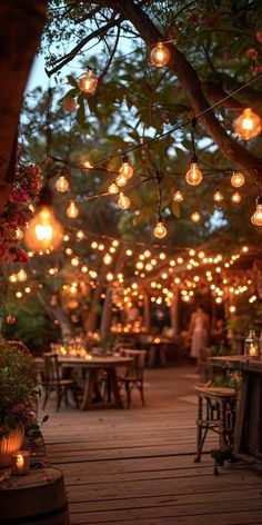 an outdoor dining area with lots of lights hanging from the trees