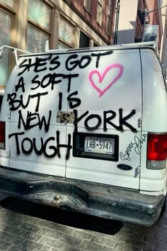 a white van with graffiti on the back parked in front of a tall brick building