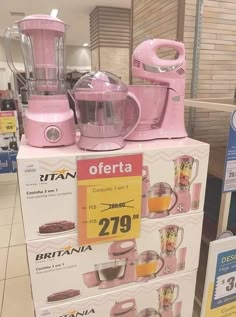 a pink blender sitting on top of a box next to other items in a store