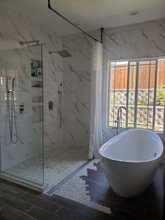 a bath tub sitting next to a window in a bathroom with marble walls and floor