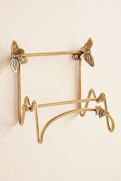 a pair of gold hair clips with butterflies on them hanging from a hook against a white wall