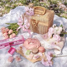 a picnic table with pink flowers and other items on it, including a basket bag