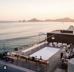 an outdoor event set up on the water's edge with tables and chairs around it