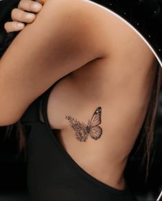 a woman's back with a butterfly tattoo on her left side ribcage