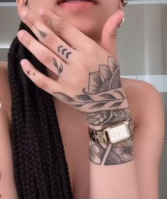 a close up of a person with tattoos on her arm and hand near her face