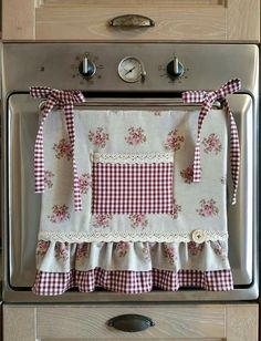 an oven with a red and white checkered apron hanging on it's side