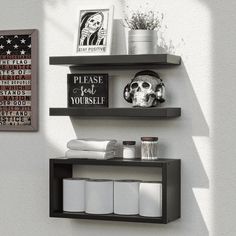 two black shelves on the wall with white towels and other items in front of them