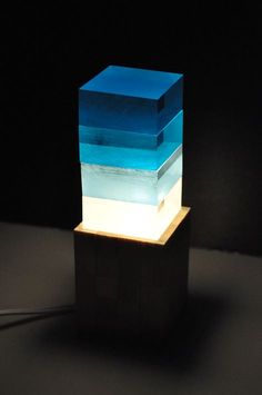 a blue and white light sitting on top of a wooden block next to a black wall