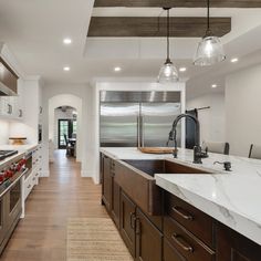 a large kitchen with an island counter top and stainless steel appliances on the wall, along with hardwood flooring