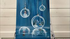 an easel painted with snow globes hanging from it's sides