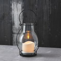 a lit candle in a glass container on a table