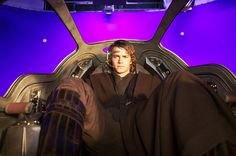 a man sitting in the back of a vehicle with his legs crossed and wearing a star wars costume