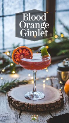 blood orange gimlet in a coupe glass on a wooden table with christmas decorations