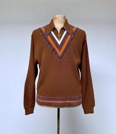 * Casual knit c 1970s * Brown Orlon acrylic knit  * Front features knit insets of orange and ivory at neck trimmed in brown faux suede * Long pointed collar is also trimmed in faux suede and features a brass zipper with ring pull closure * Long, set-in sleeves feature ribbed cuffs * Front hem features an orange knit inset bordered by brown faux suede bands * Back hem features wide ribbing * Pulls over head Label: Macrae Quality Apparel, 100% Virgin Orlon Acrylic Excellent condition Chest: 44 Shoulder: 19 Sleeve: 26 Length: 25 Garments are flat-measured. Please compare these measurements to another flat-measured garment that fits you correctly for size comparison. Don't forget to leave room for body movement.  Please view my Shop Policies prior to placing an order as all sales are final: ht Retro Collared Sweater For Fall, Retro Brown Knit Sweater, Retro Brown Long Sleeve Cardigan, Vintage Brown Long Sleeve Sweater, 70s Wool Sweater, 1970s Knitwear, 70s Fashion Men, 1970s Sweater, Hipster Sweater