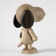 a wooden figurine of a dog with a black nose and tail, on a white background