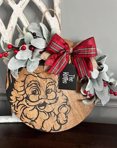 a wooden sign with a santa claus face and holly wreath on it's side