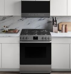 a kitchen with marble counter tops and stainless steel stove top, oven hood, and range