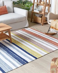 a living room filled with furniture and a rug on top of a wooden floor next to a window