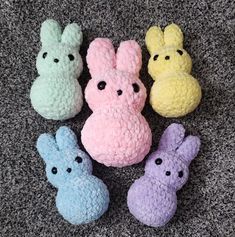 four small crocheted stuffed animals sitting next to each other on a carpeted floor