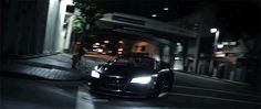 a black sports car driving down a street at night