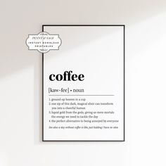 a coffee sign hanging from the side of a white wall next to a chair and table