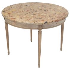 a round marble top table with wooden legs and an ornate design on the base, against a white background