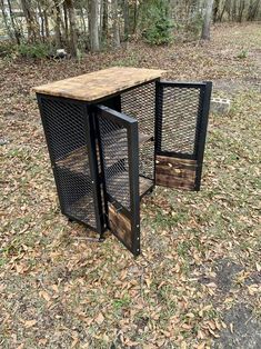 two metal and wood crates sitting in the grass next to some trees with leaves on them