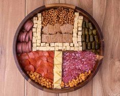 a wooden platter filled with different types of meats, cheese and crackers