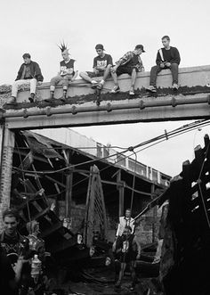 black and white photograph of men sitting on top of a bridge