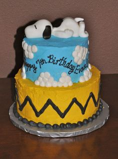 a birthday cake decorated with snoopy and clouds