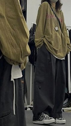 two people standing next to each other in front of clothing racks