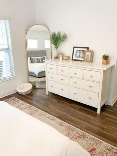 a bedroom with a bed, dresser and mirror