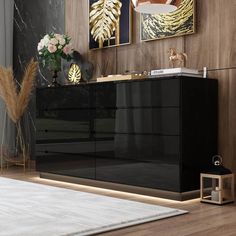 a black and gold sideboard in a living room with art on the wall behind it