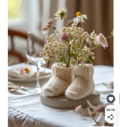 there is a vase with some flowers in it and two baby booties on the table