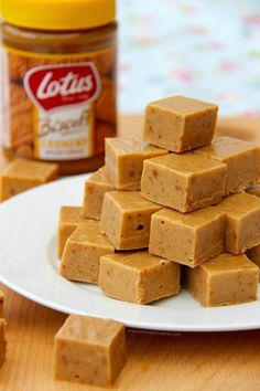 several pieces of peanut butter fudge on a white plate next to a jar of peanut butter