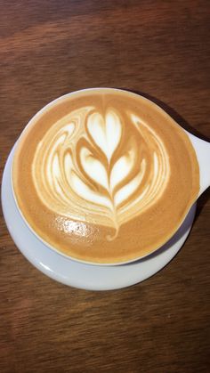 a cappuccino on a white saucer with a leaf drawn in it